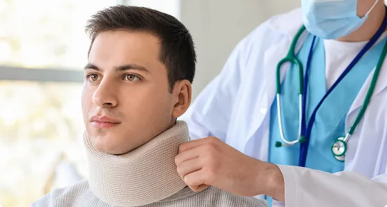 Healthcare professional fitting cervical collar on young male patient indoors.