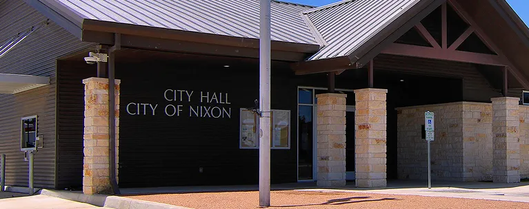 Exterior view of City Hall building with stone pillars and "City of Nixon" signage.