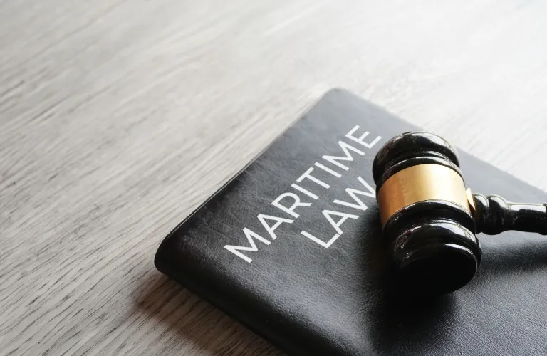 Black hardcover book titled "Maritime Law" with a wooden judge's gavel resting on it.